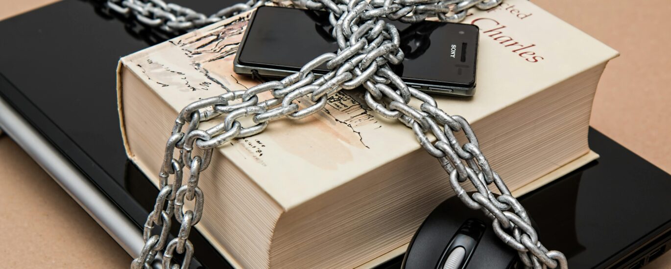 Chain-locked book, phone, and laptop symbolizing digital and intellectual security.