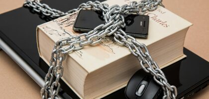 Chain-locked book, phone, and laptop symbolizing digital and intellectual security.