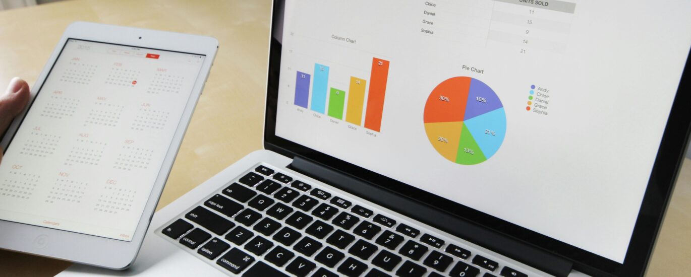Laptop displaying charts and graphs with tablet calendar for data analysis and planning.