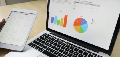 Laptop displaying charts and graphs with tablet calendar for data analysis and planning.