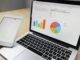 Laptop displaying charts and graphs with tablet calendar for data analysis and planning.